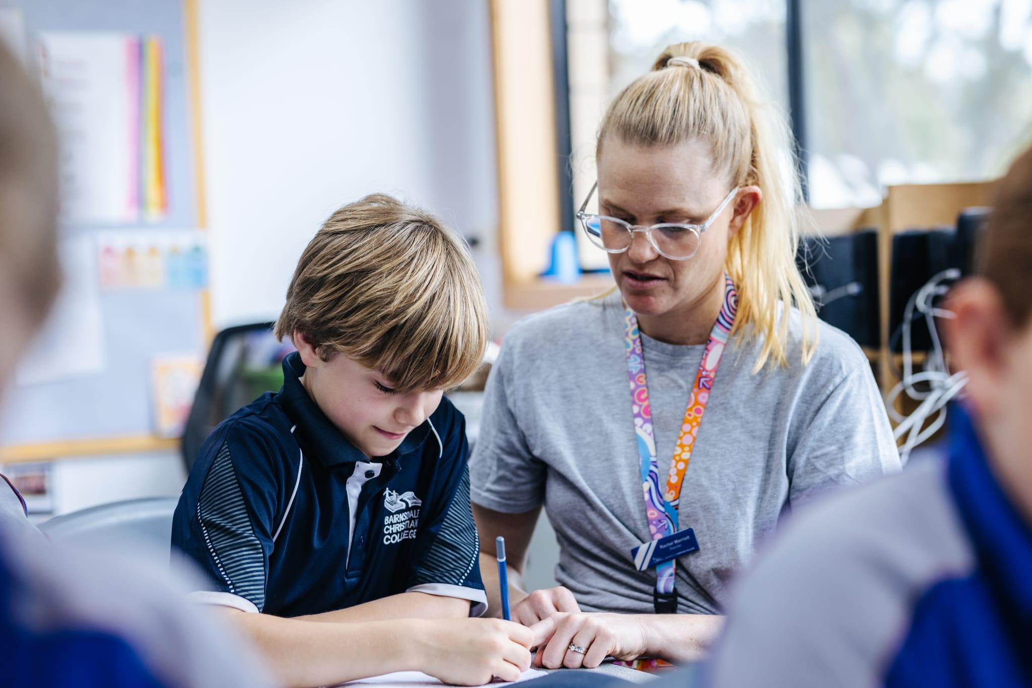 Teacher at Bairnsdale Christian College helping a student with maths during lunch break, showcasing the school's commitment to being 'Well Loved' by putting students' best interests first.