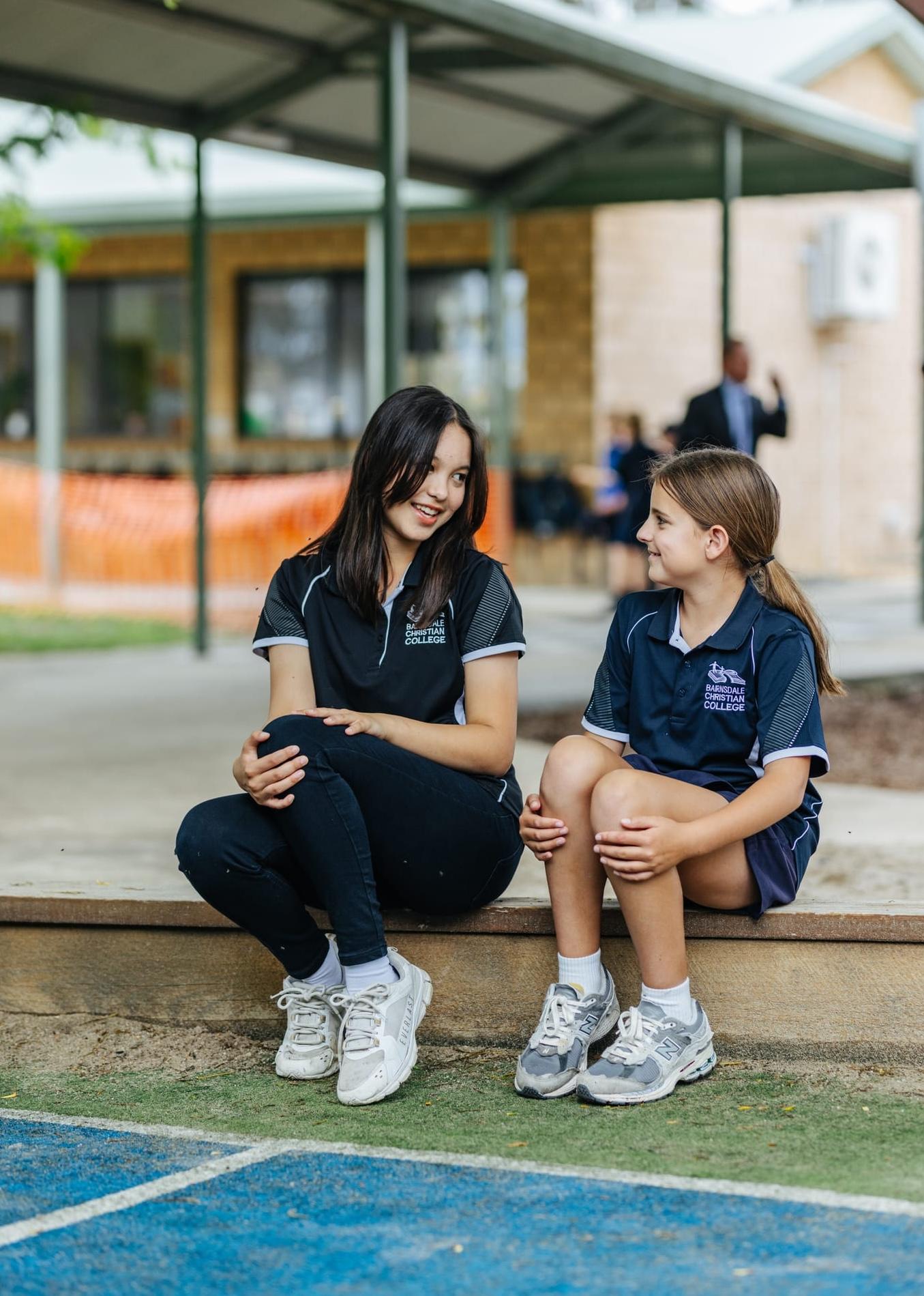 Primary school students smiling and welcoming arrivals during a school tour outdoors.